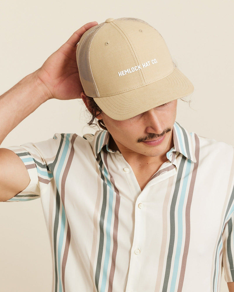 Hemlock male model looking down wearing Emerson Trucker Hat in Khaki close up