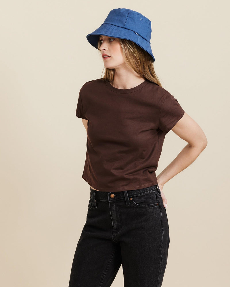 Hemlock female model looking left wearing Isle Cotton Bucket Hat in Indigo