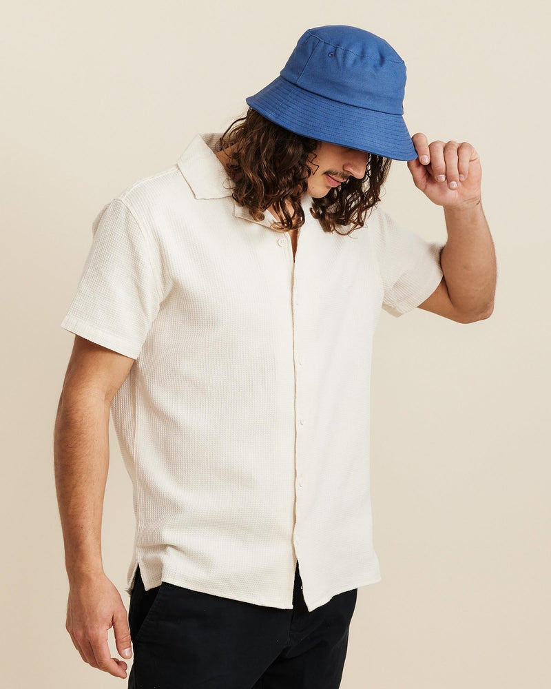 Hemlock male model looking down wearing Isle Cotton Bucket Hat in Indigo