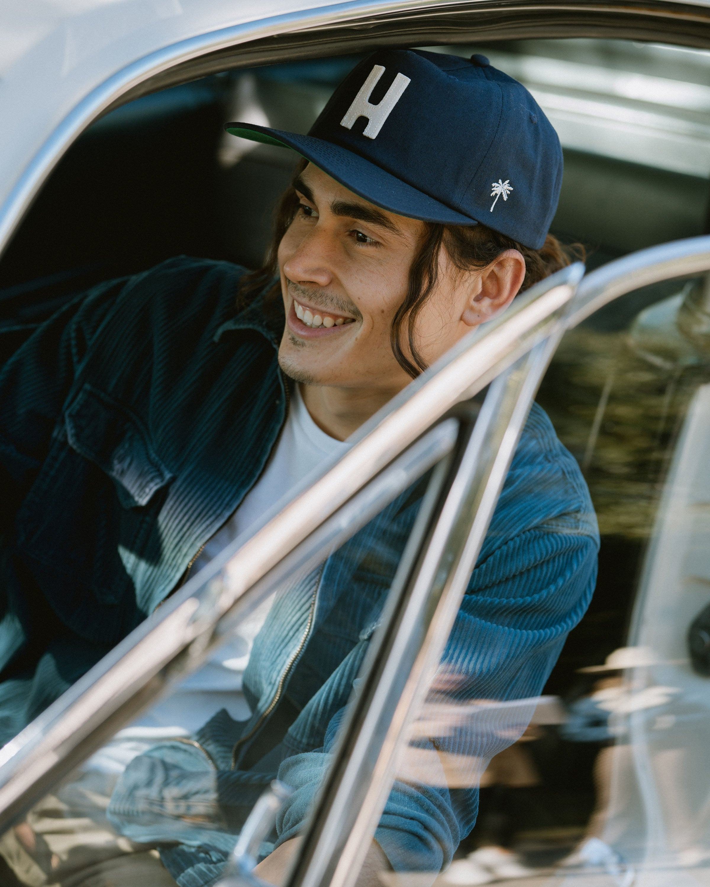 Hemlock male model looking left wearing Thomas Baseball Hat in Navy inside car