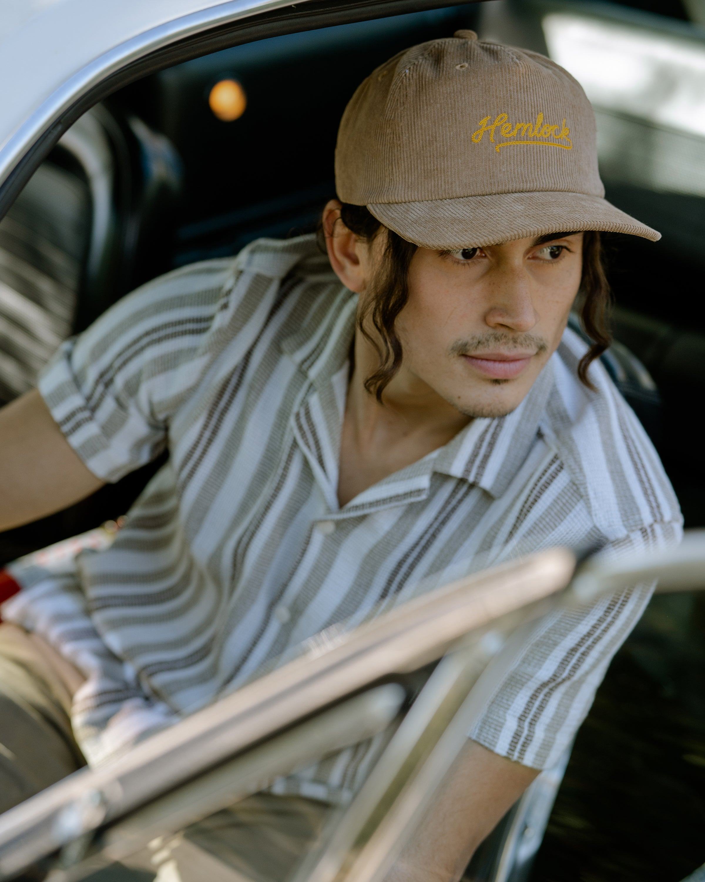 Hemlock female model looking right wearing Hemlock Wesley Corduroy Baseball Hat in Spice inside car