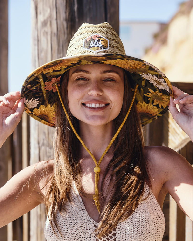 Hemlock female model smiling looking straight wearing Woodstock straw lifeguard hat with sunflower pattern