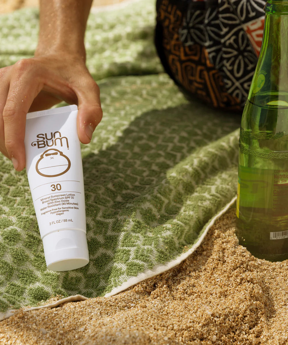 Sun Bum® Mineral SPF 30 Sunscreen Lotion by a beach towel
