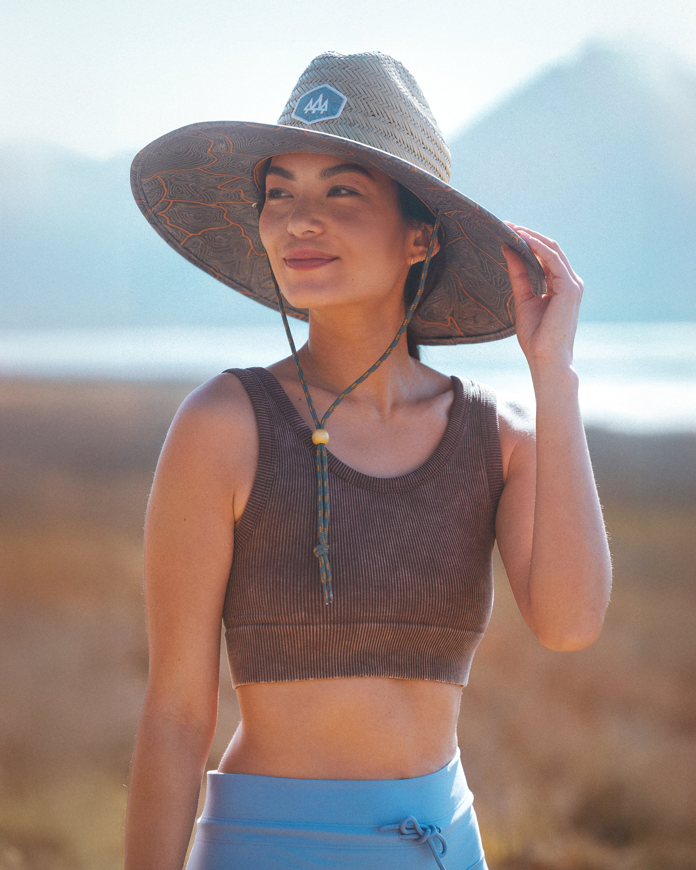 Hemlock female model wearing the UPF50+ Lifeguard Straw Hat Nomad Topography print during a hike