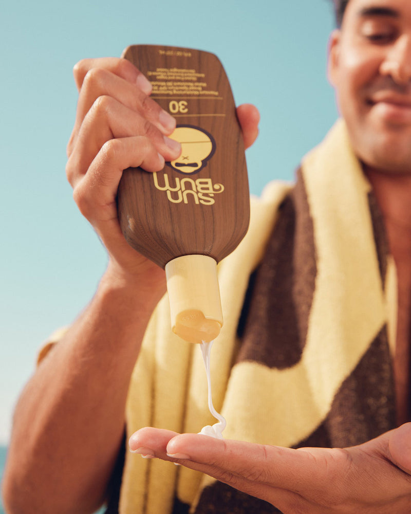 Sun Bum SPF 30 Original Sunscreen Lotion bottle front view with model at beach.