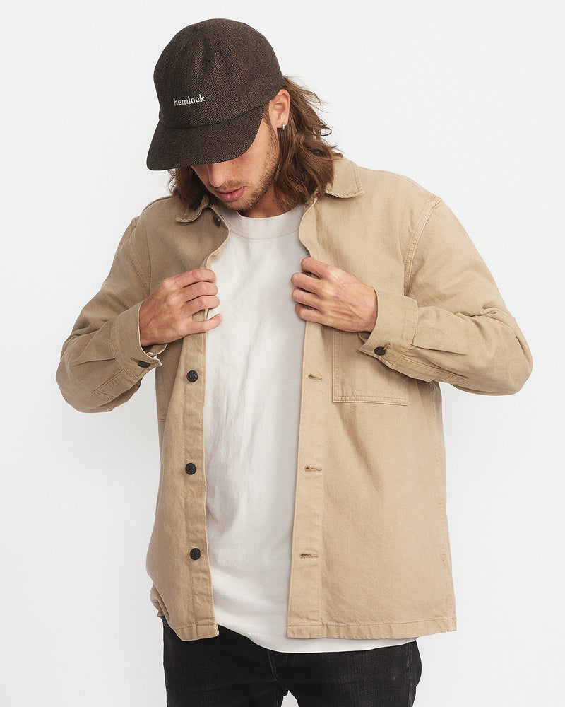 Hemlock male model looking down wearing Bristol Dad Hat in Brown and Black