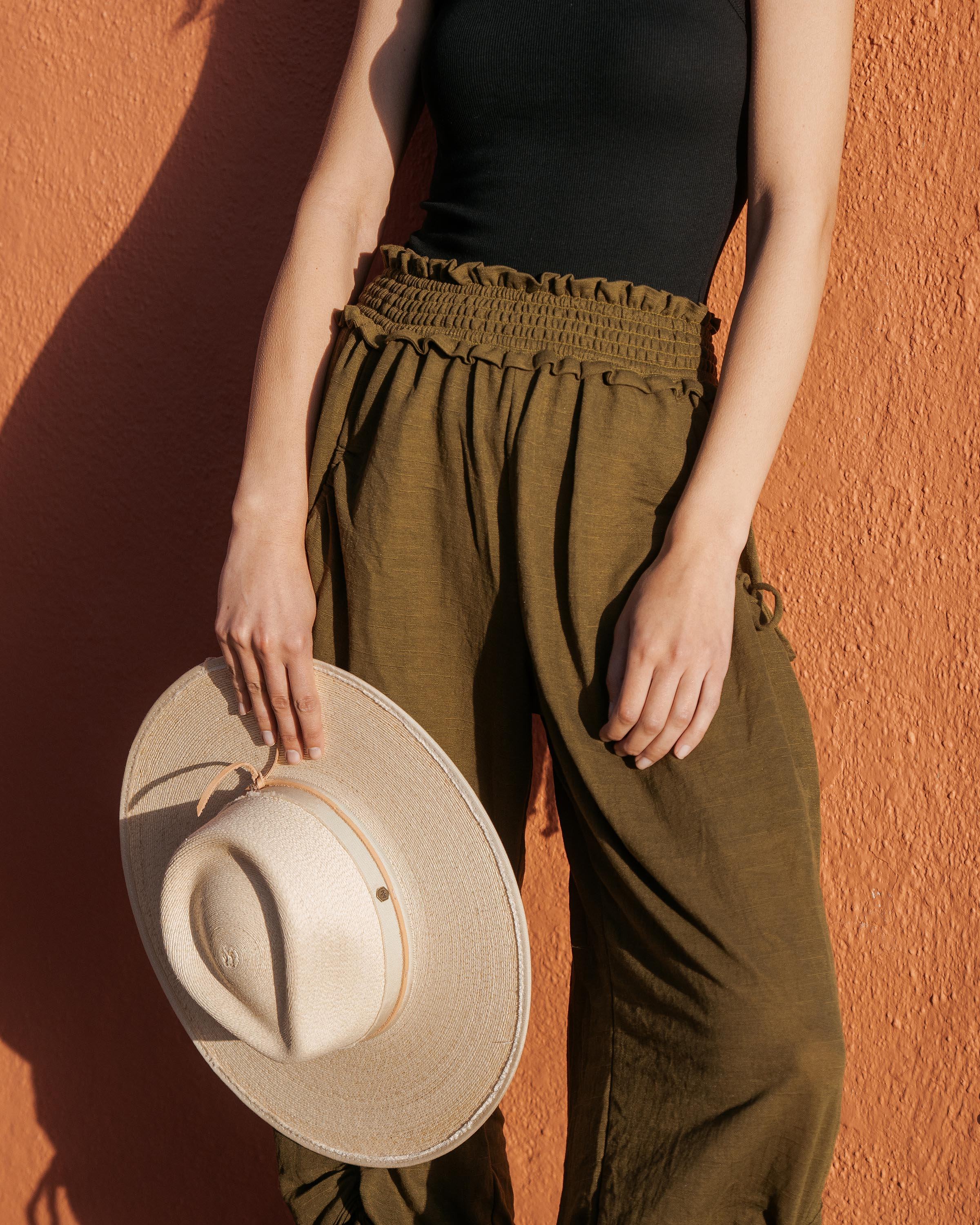 Hemlock female model holding Cruz Straw Fedora in Sand color