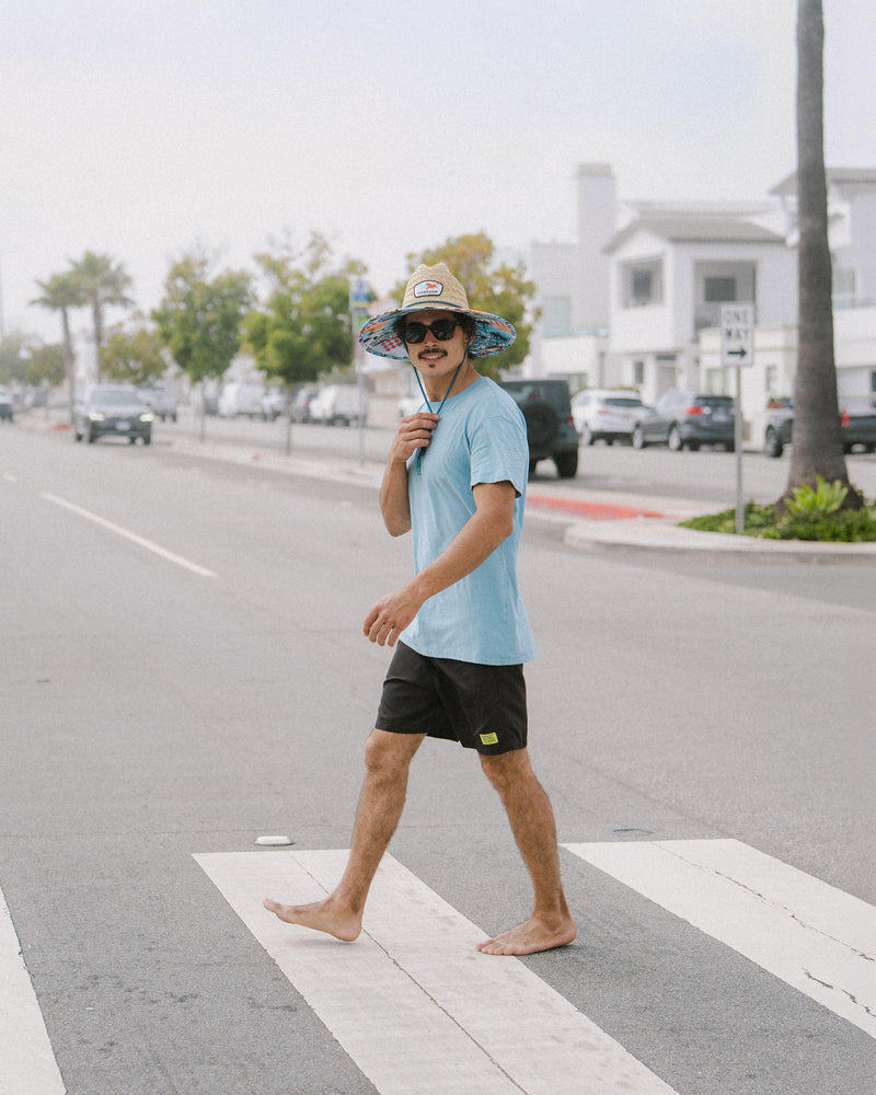 Hemlock male Model wearing the
UPF50+ Lifeguard hat in Racing Legend print crossing the street
