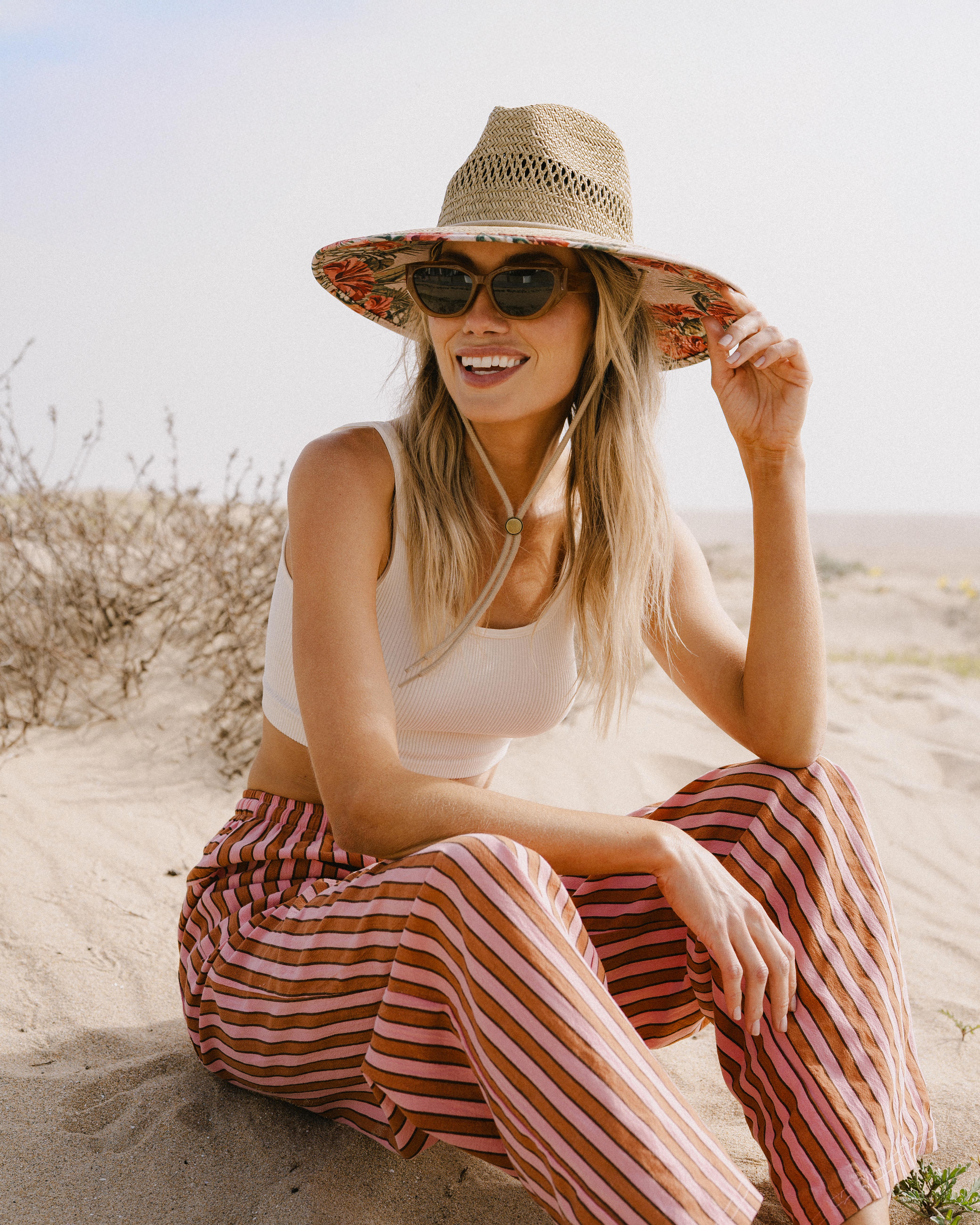 Hemlock female Model wearing the
UPF50+ Lifeguard hat in Hibiscus
print sitting at the beach