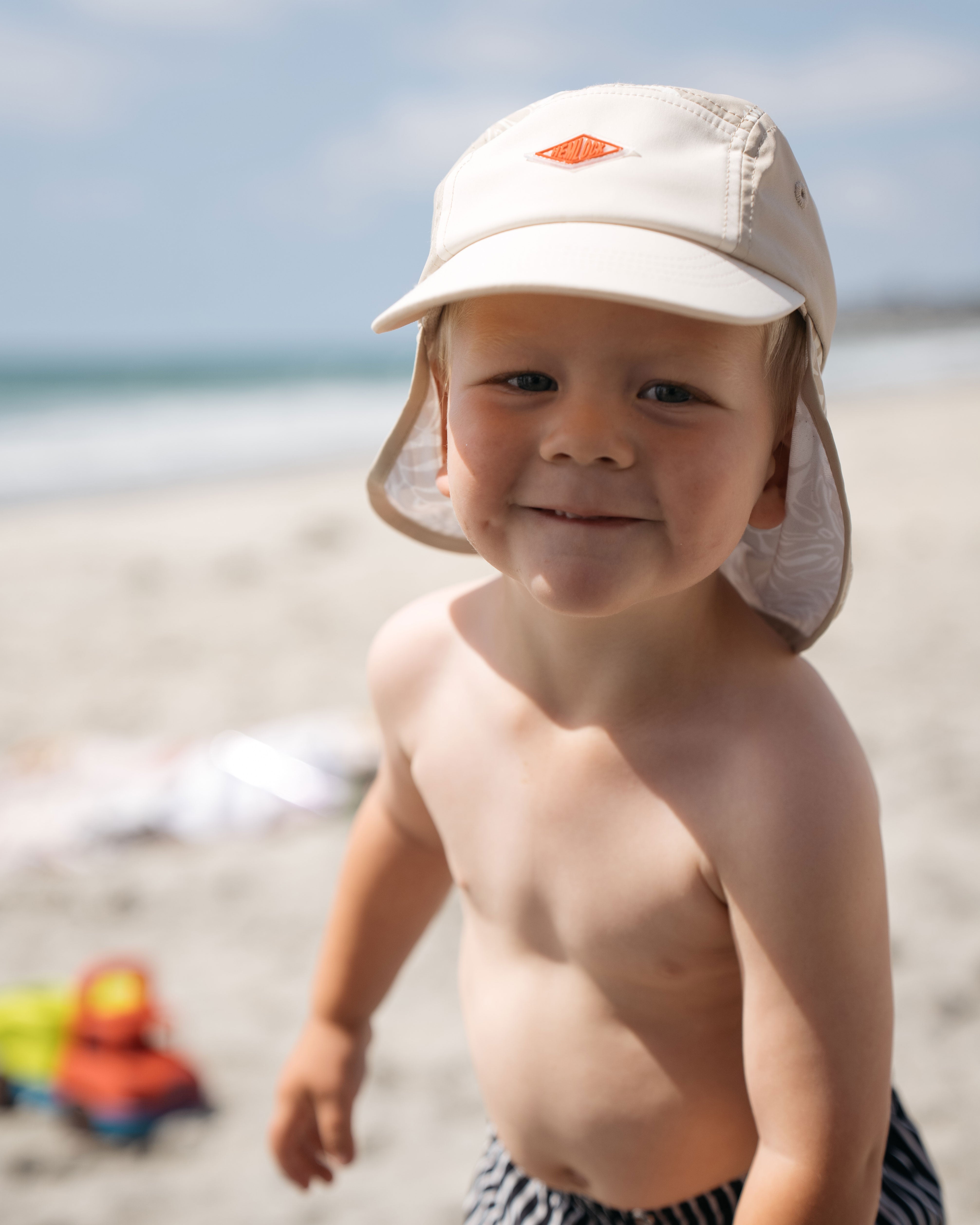 Baby boy hemlock model wearing the surfari cap at the beach