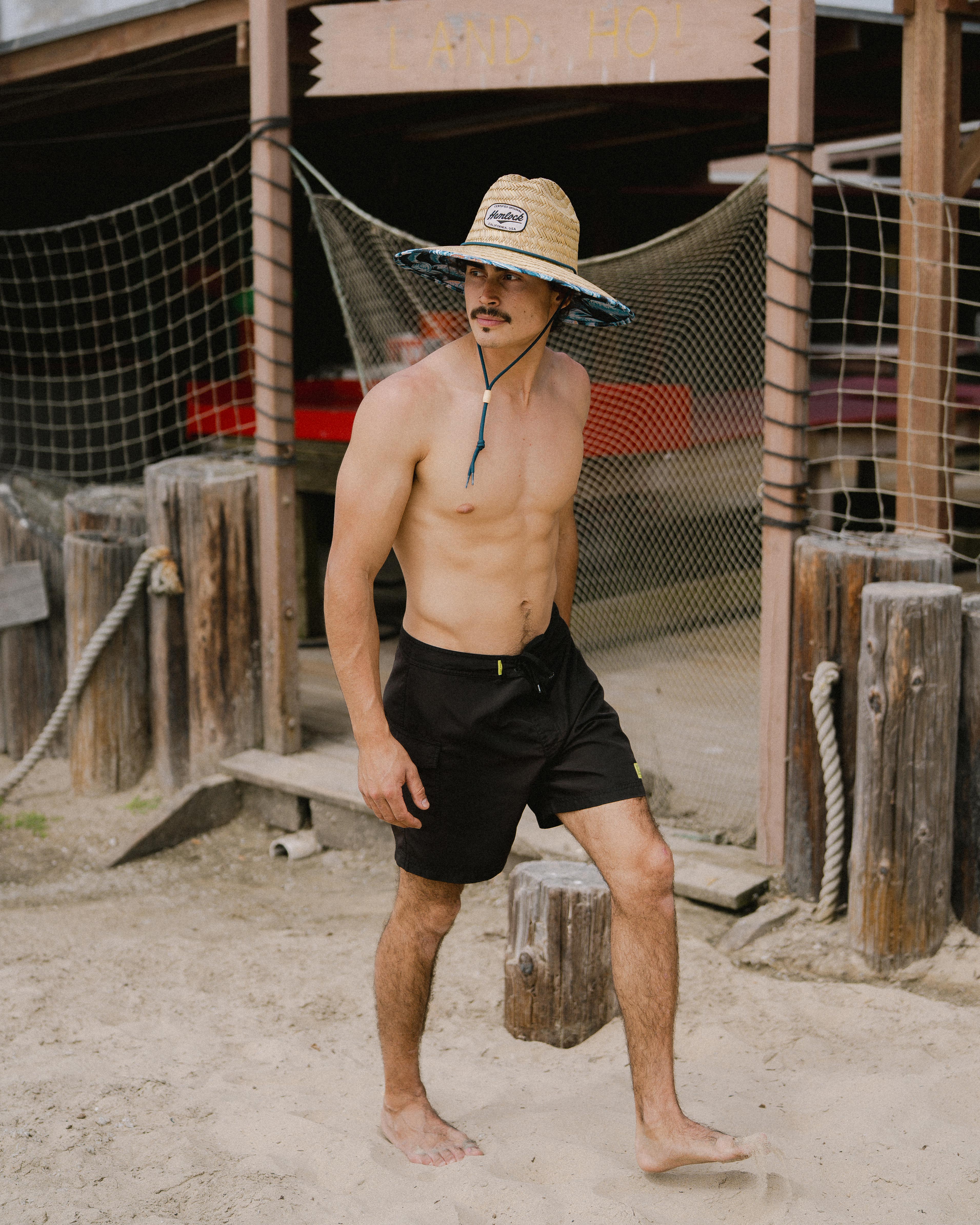 Hemlock male Model wearing the
UPF50+ Lifeguard hat in Blue Fish
print walking at the beach