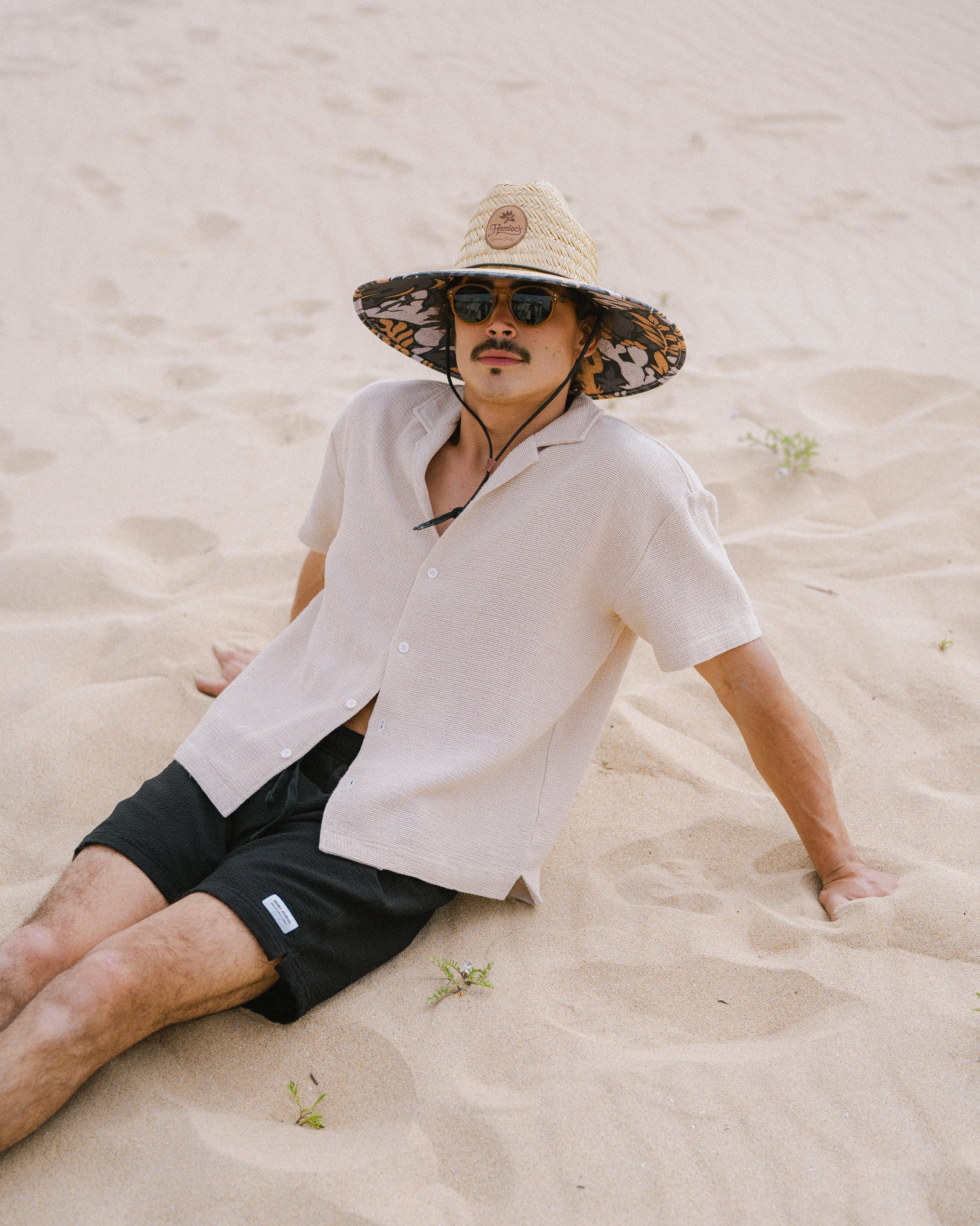 Hemlock male Model wearing the
UPF50+ Lifeguard hat in Desert Bloom
print sitting at the beach