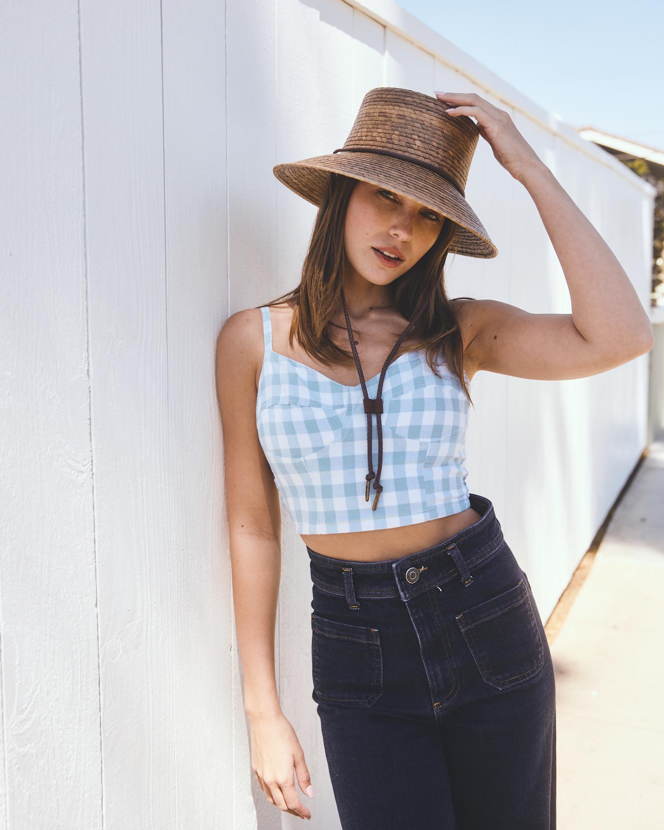 Hemlock female model wearing the Leon Straw Bucket Hat in Toast standing by a white wall