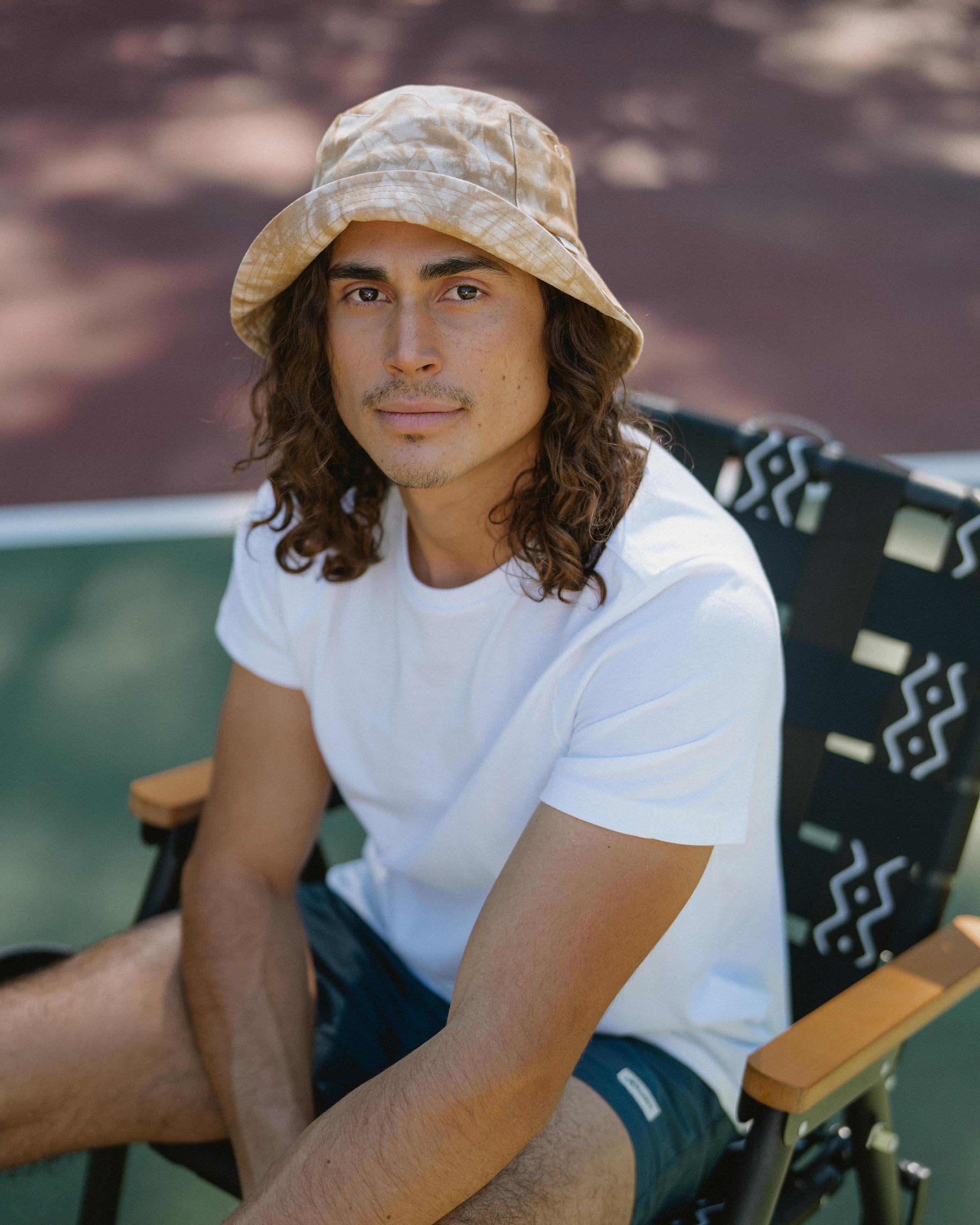 Hemlock male model looking straight wearing Isle Cotton Bucket Hat in Saffron Tie-dye