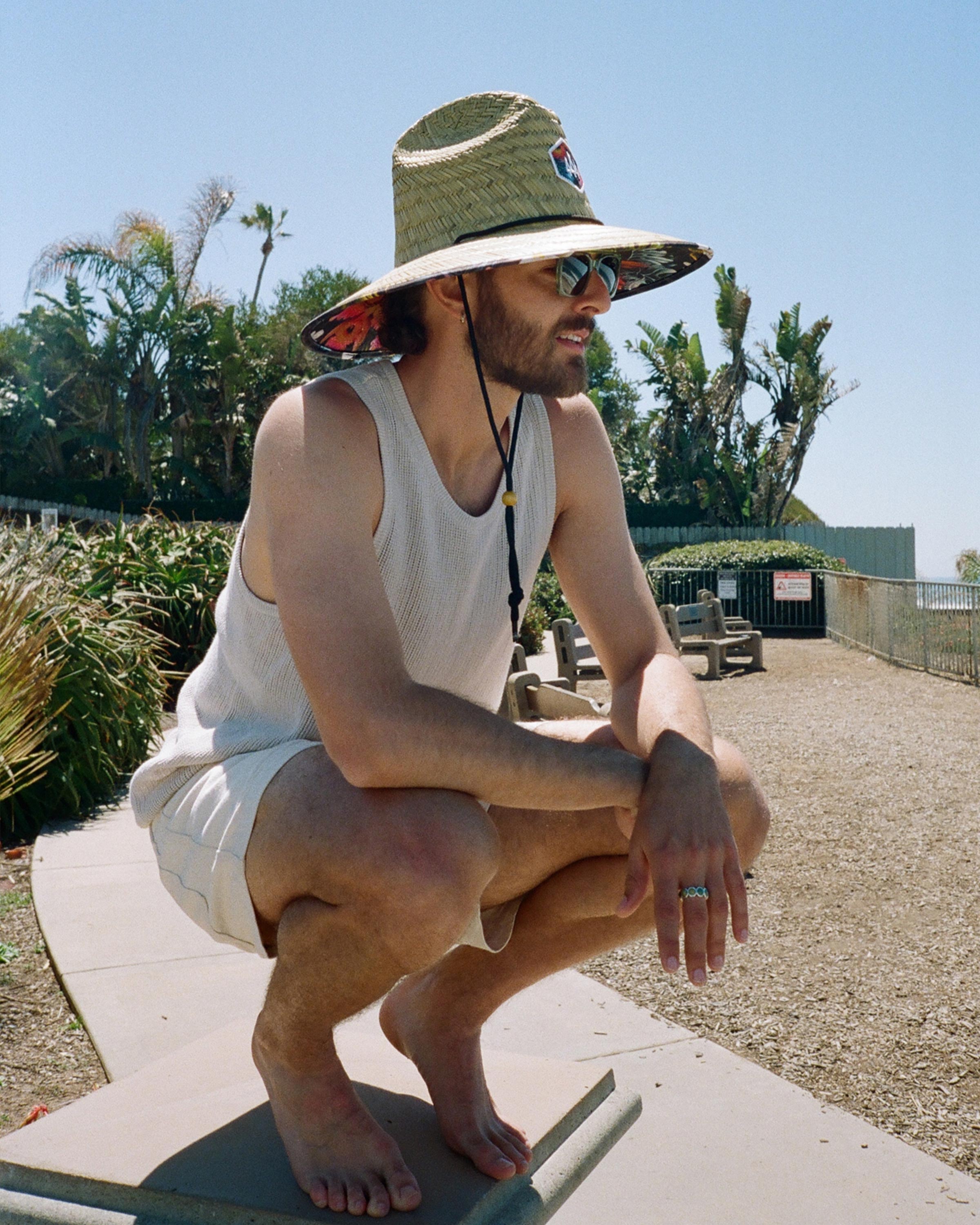 Hemlock male model looking right wearing Kailua straw lifeguard hat with hawaiian floral pattern