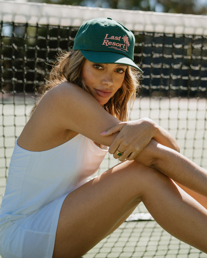 Hemlock female model looking over her shoulder wearing Hemlock Last Resort Baseball Hat in Clover