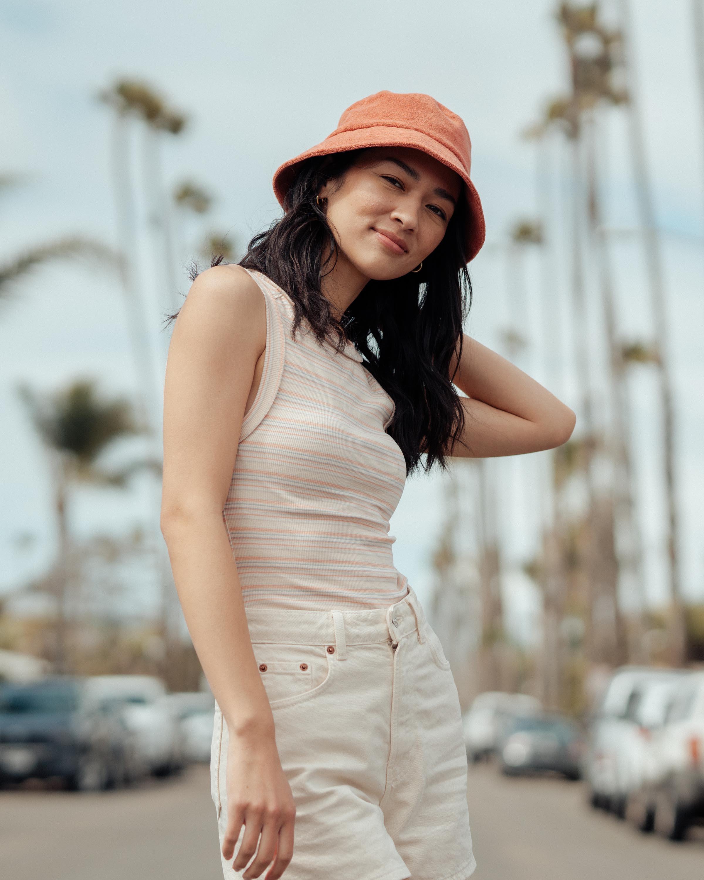 Hemlock female model looking down wearing Marina Terry Bucket Hat in Red Clay