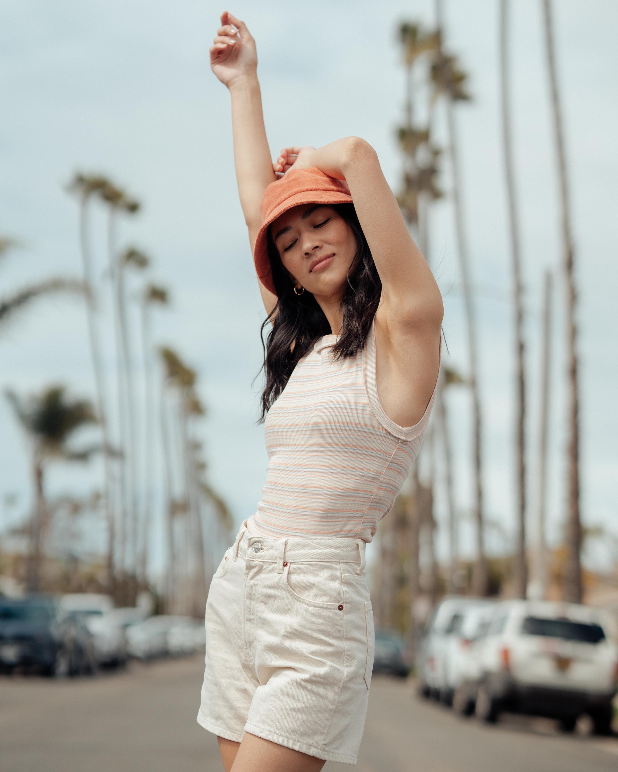 Hemlock female model looking down wearing Marina Terry Bucket Hat in Red Clay 