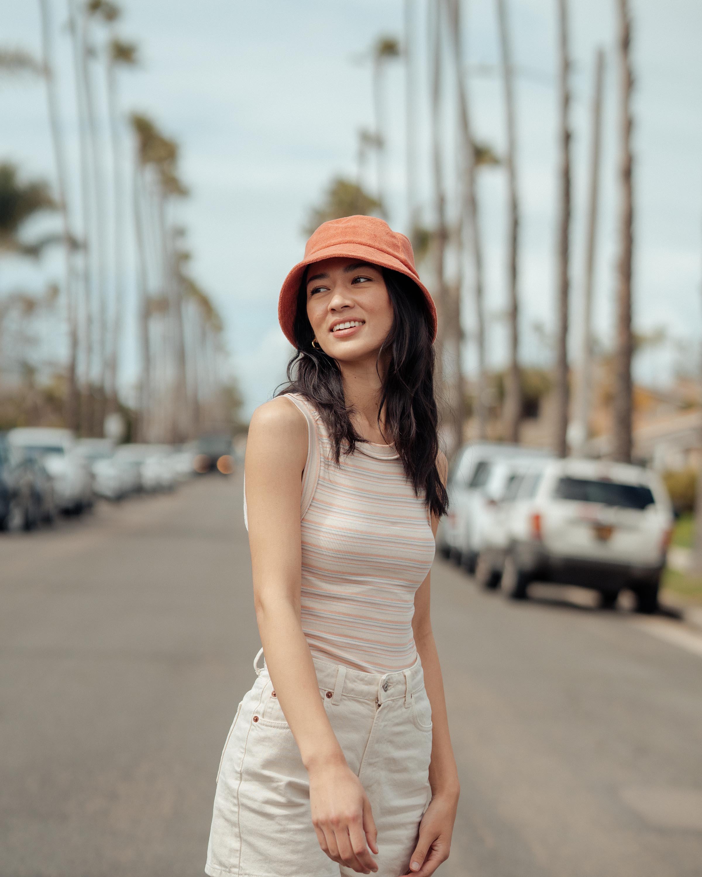 Hemlock female model looking left wearing Marina Terry Bucket Hat in Red Clay