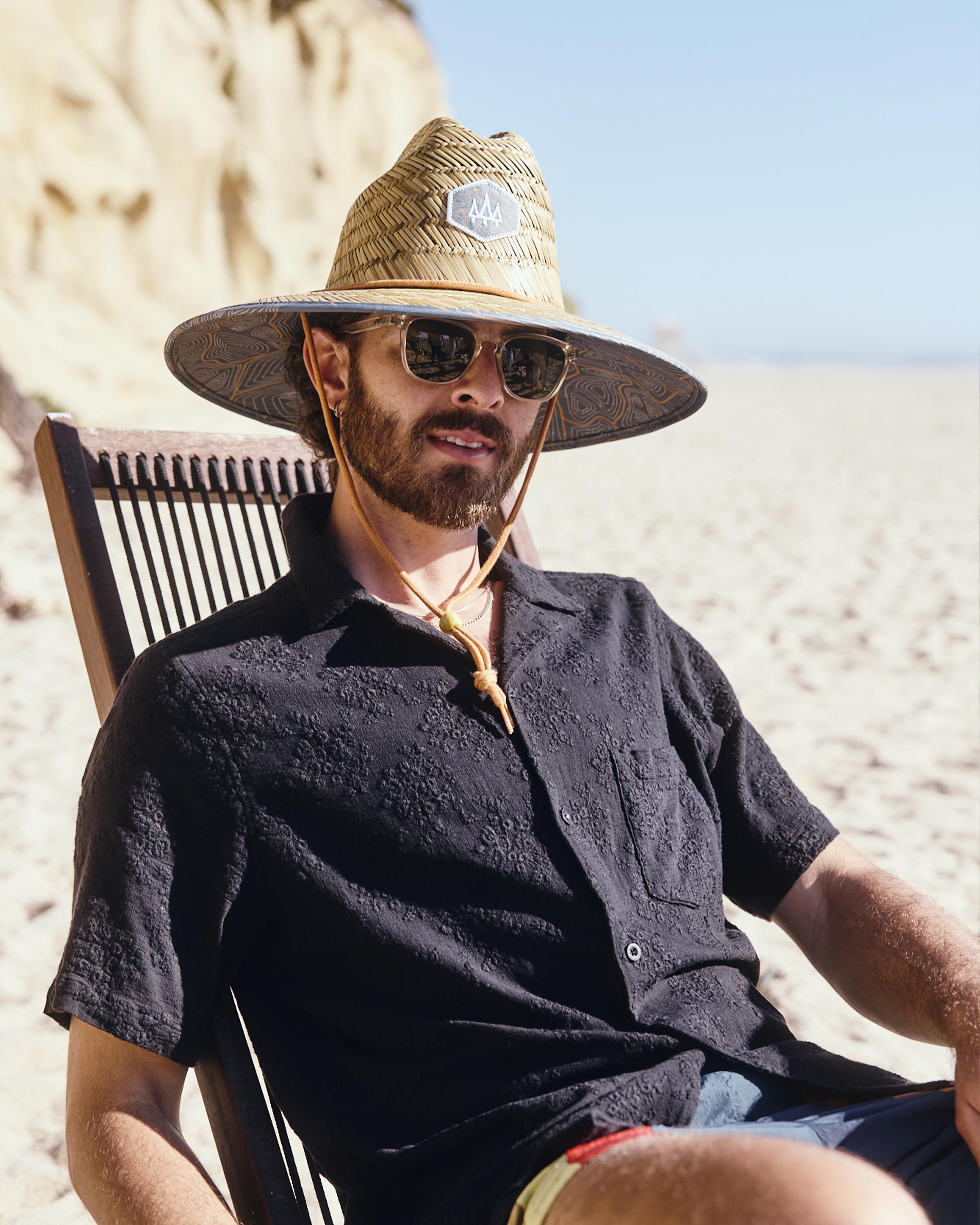 Hemlock male model wearing Nomad straw lifeguard hat with topography pattern at the beach