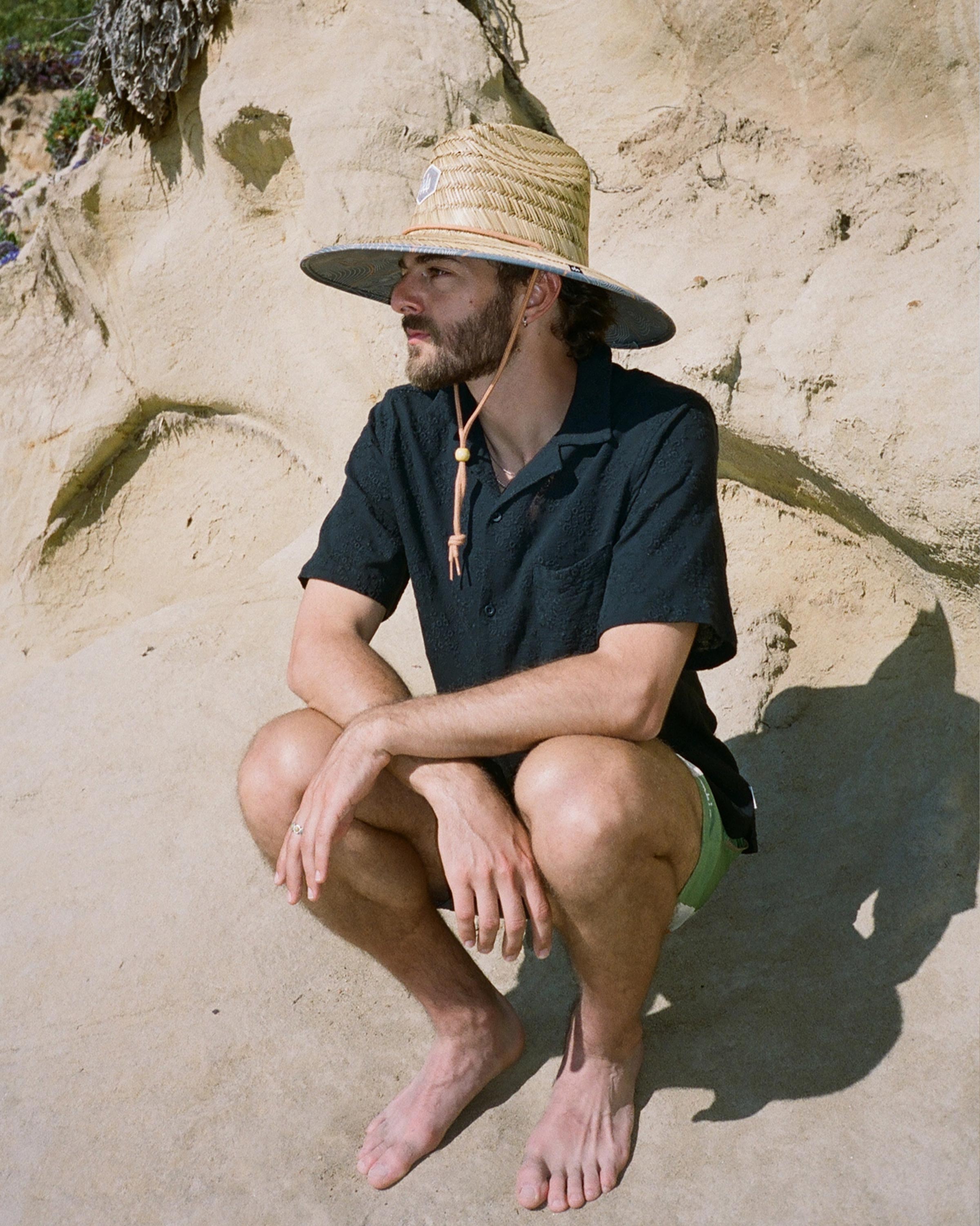 Hemlock male model looking left wearing Nomad straw lifeguard hat with topography pattern