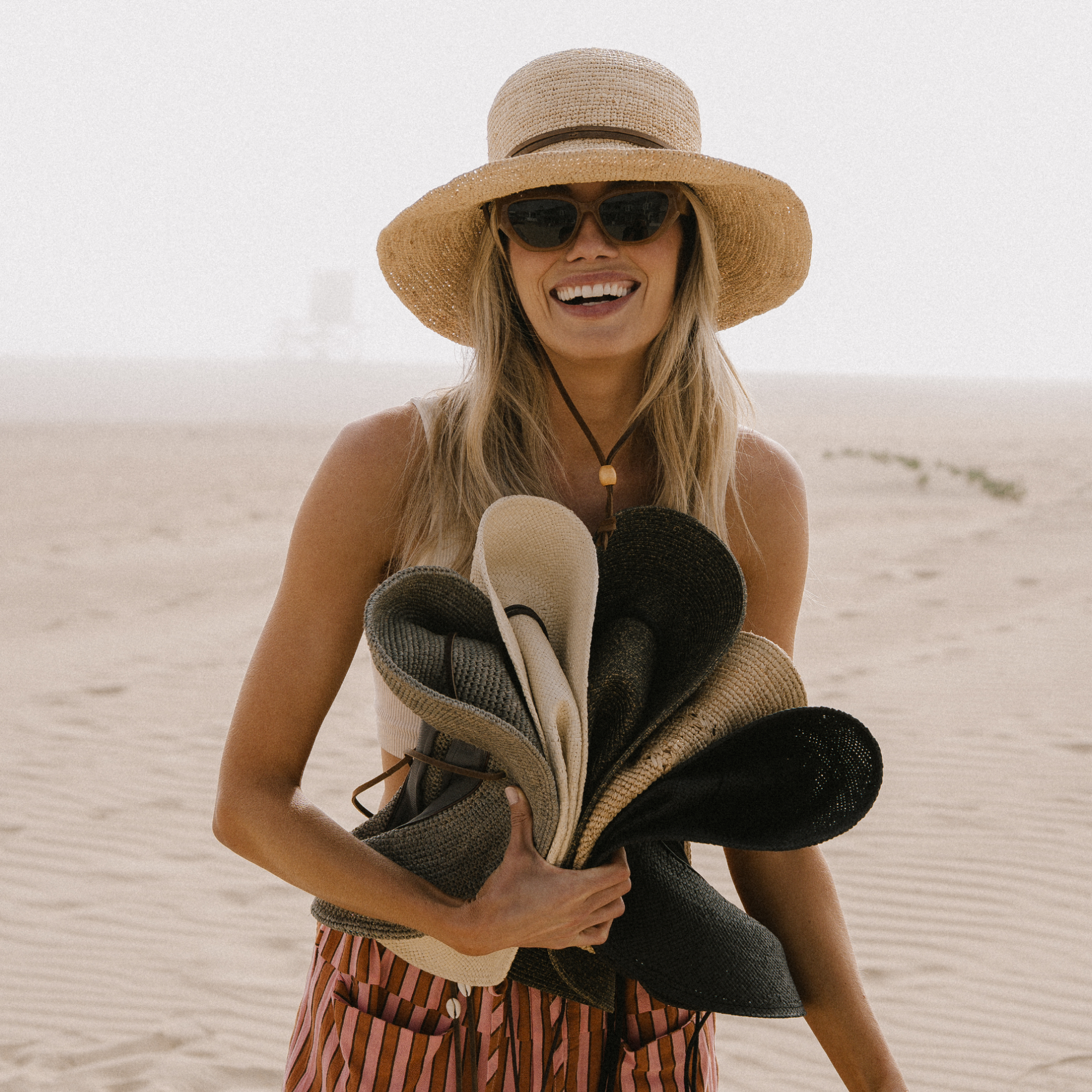 hemlock female model wearing the bondi bucket packable hat and holding 5 packable hats 