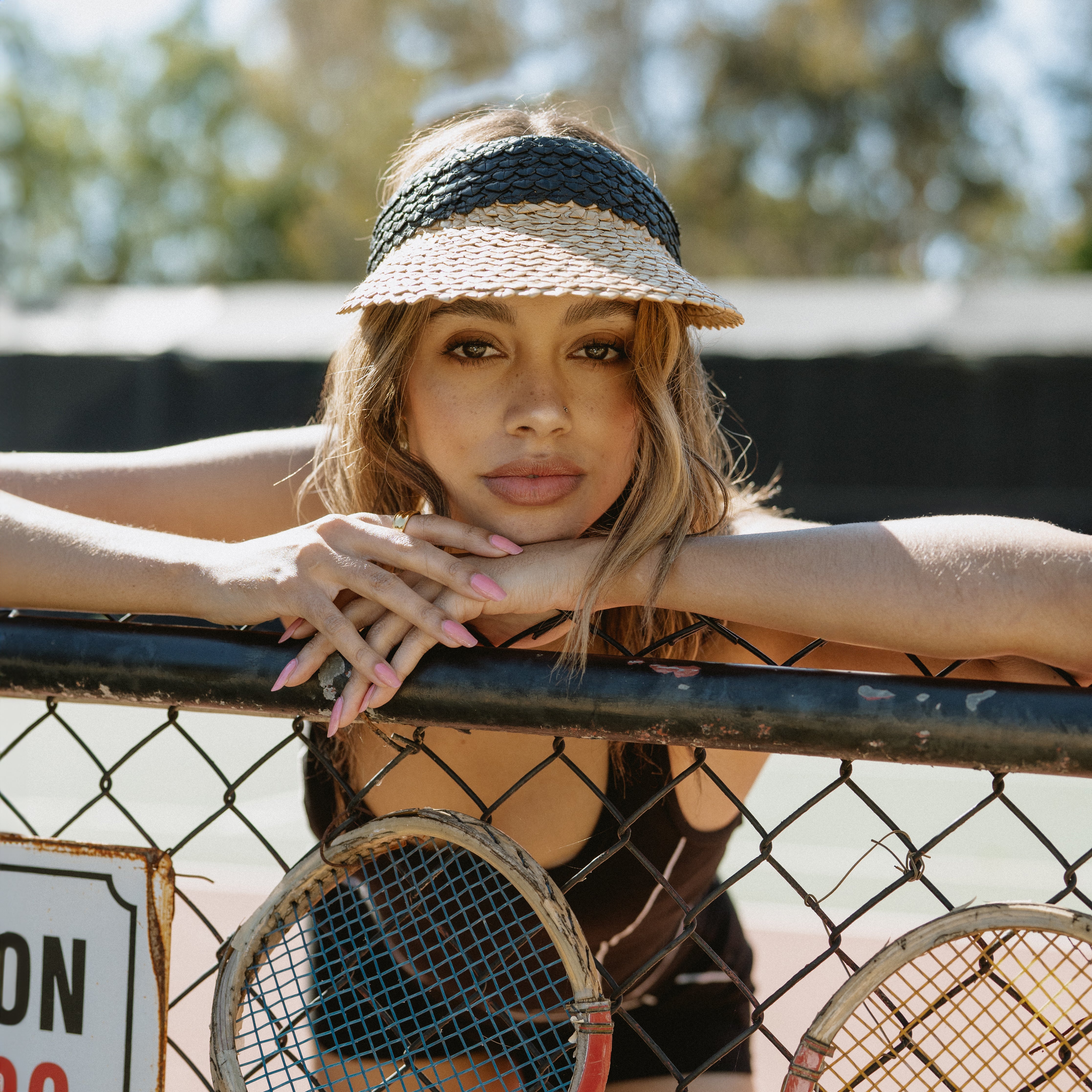 Female model wearing Capri Visor on tennis court.