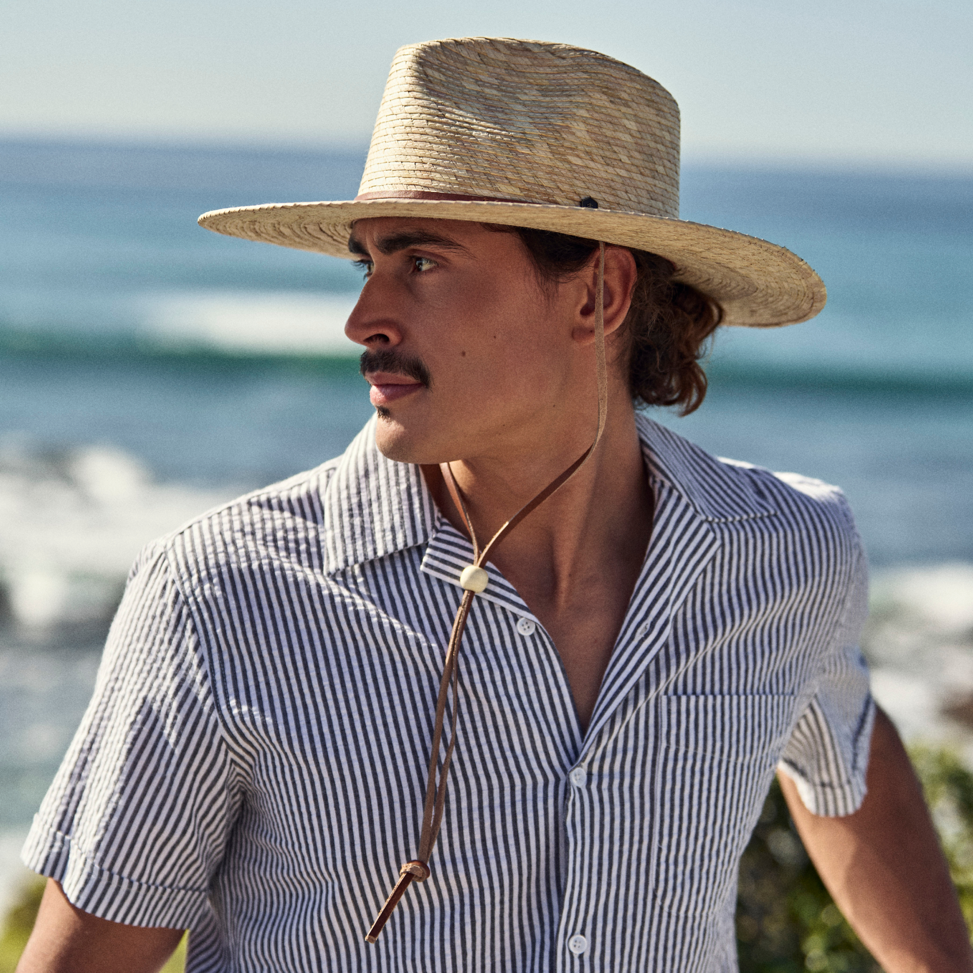 hemlock male model wearing the morro straw fedora by the beach - straw hats collection card