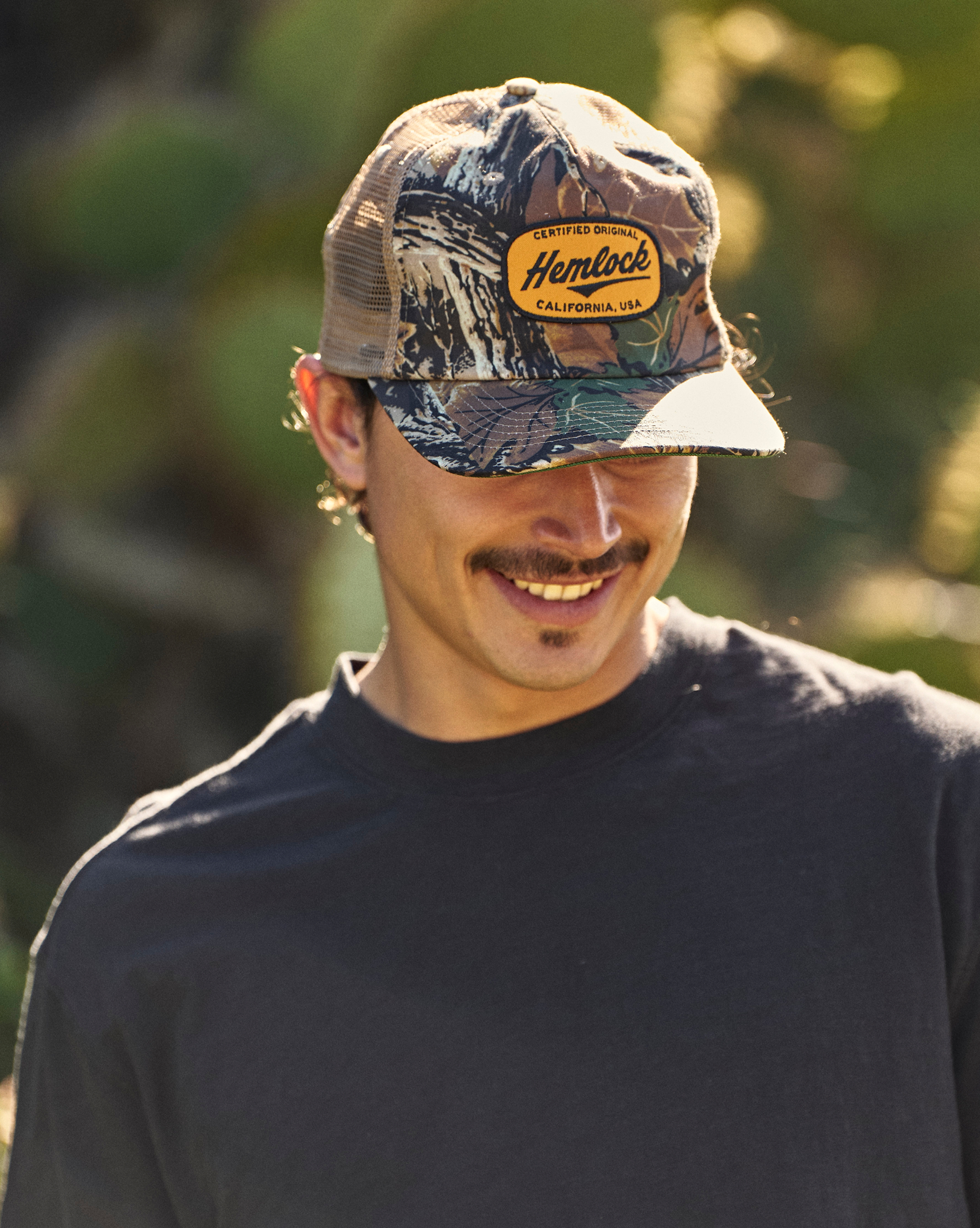 Hemlock male model wearing the Fischer Trucker Hat Realtree® Advantage Camo at a hike