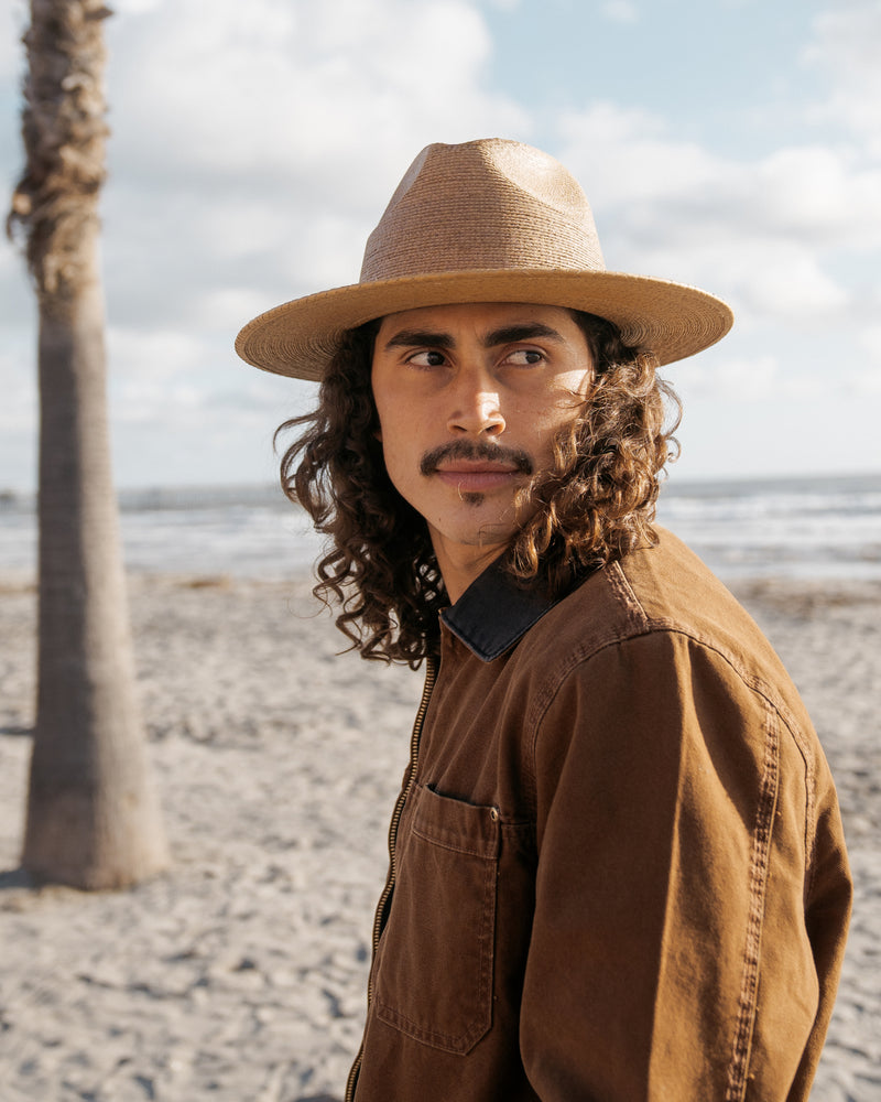 Hemlock male model wearing the Botero Straw Fedora in Saddle by the beach