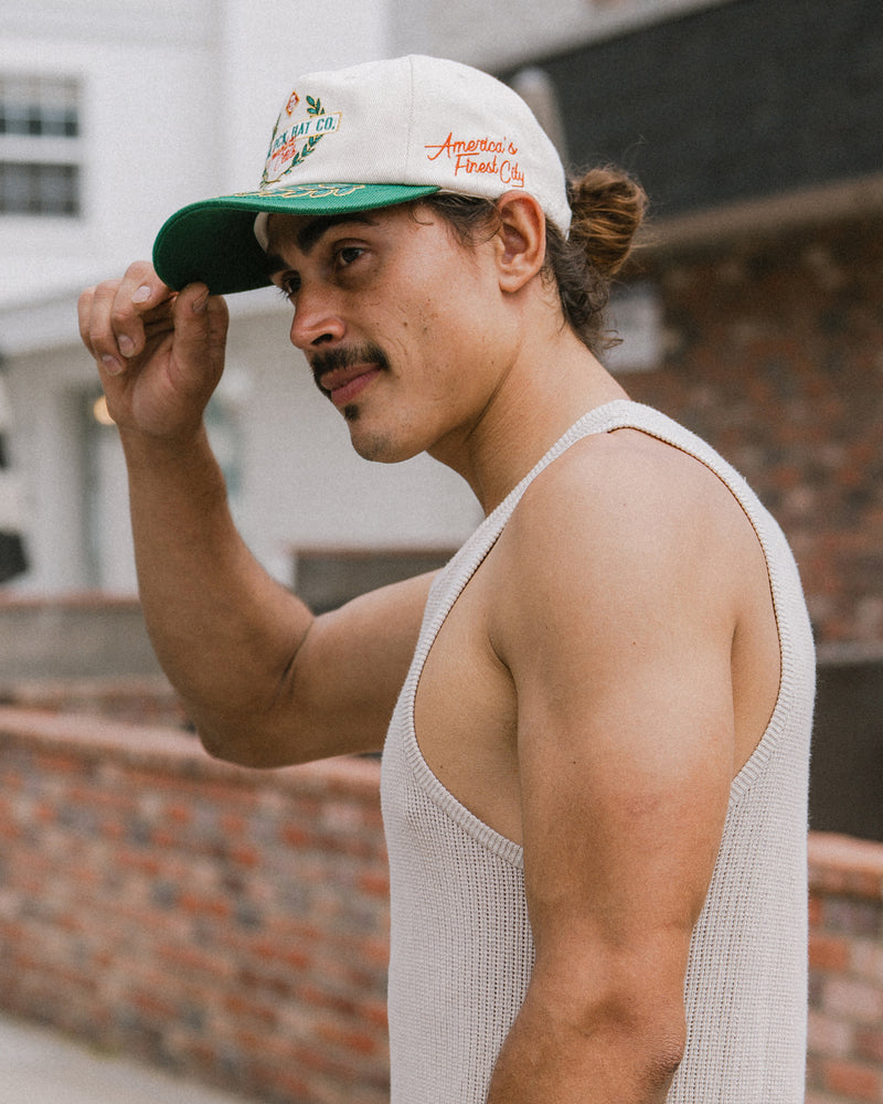 Hemlock male model wearing the Fairway baseball hat in emerald side embroidery