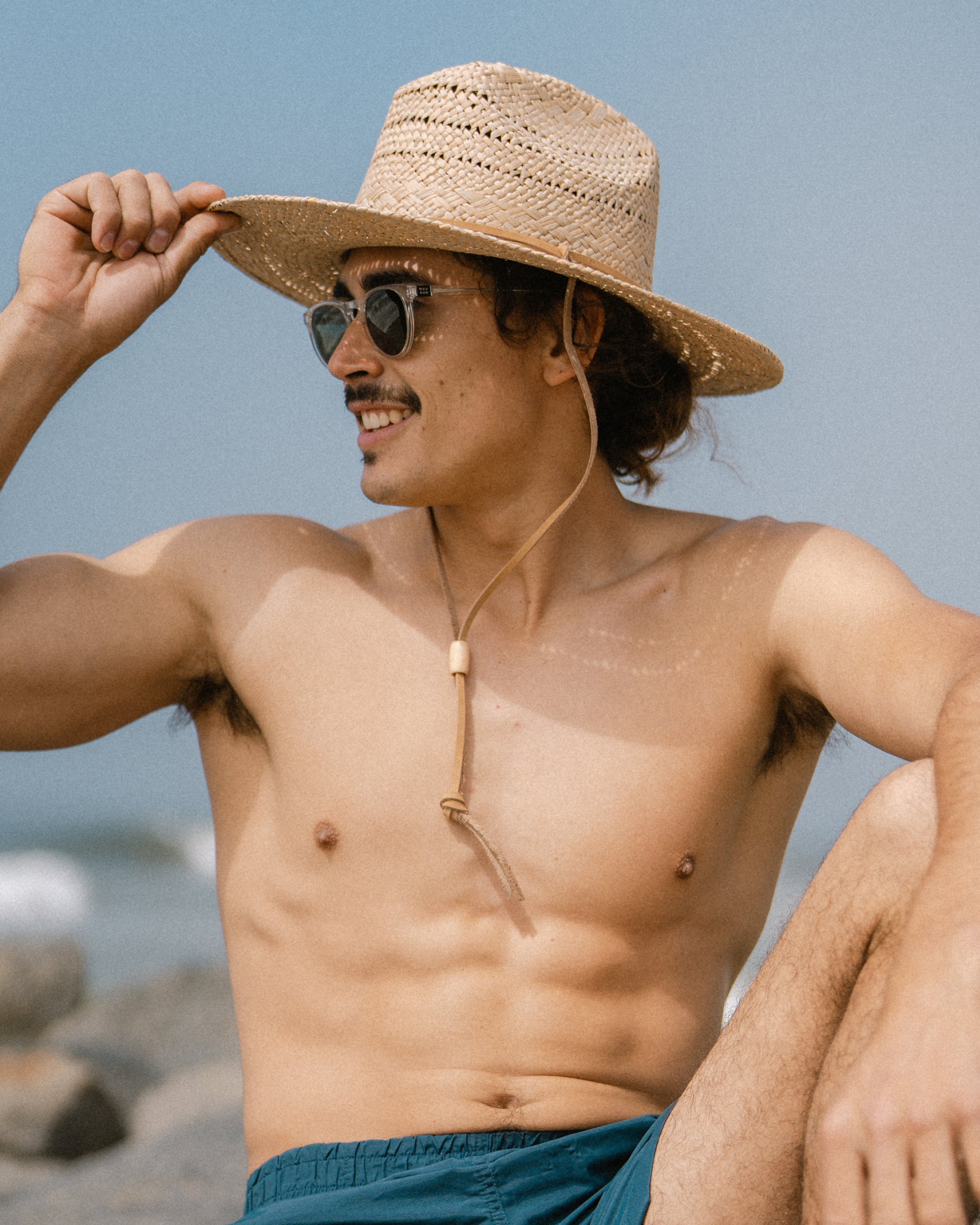 Hemlock male model wearing Grandview straw hat on a beach 