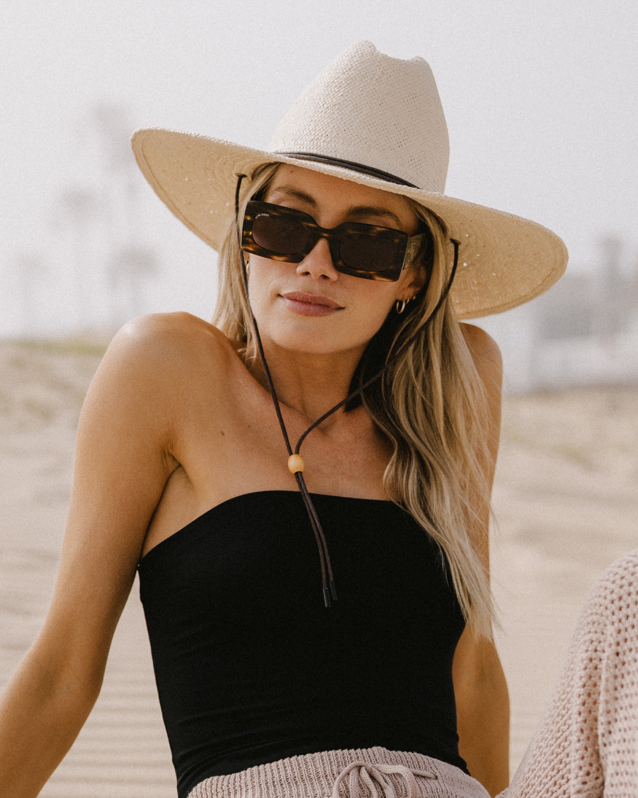 Woman wearing a wide-brimmed hat on a beach.