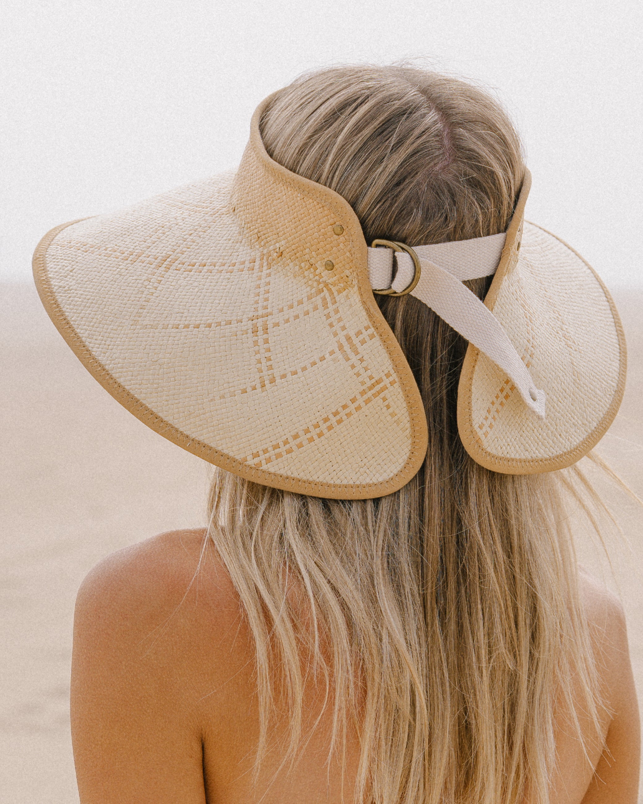 Hemlock female model wearing the Luna packable wide brim straw visor in sand color adjustable back
