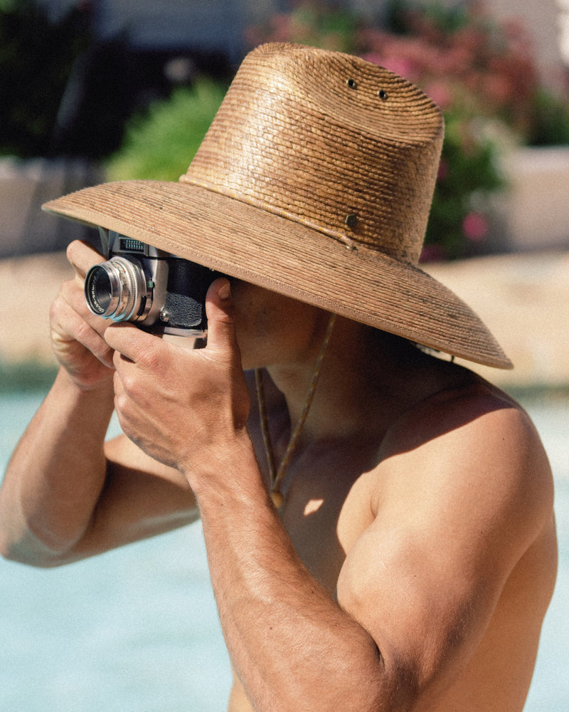 Hemlock male model wearing the Santos Lifeguard Straw Hat in Toast by the pool side profile