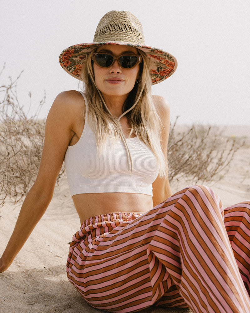 Hemlock female model wearing the UPF50+ Lifeguard hat in Hibiscus print at the beach