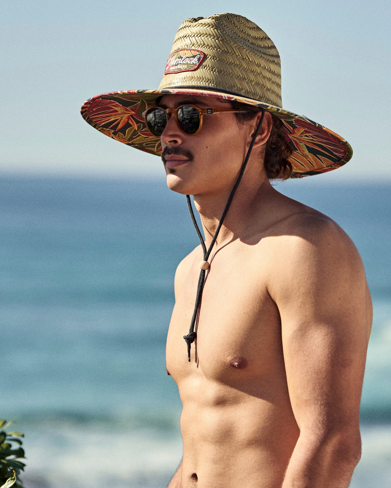 Hemlock male model wearing the UPF50+ Lifeguard hat in tropical foliage print at the beach