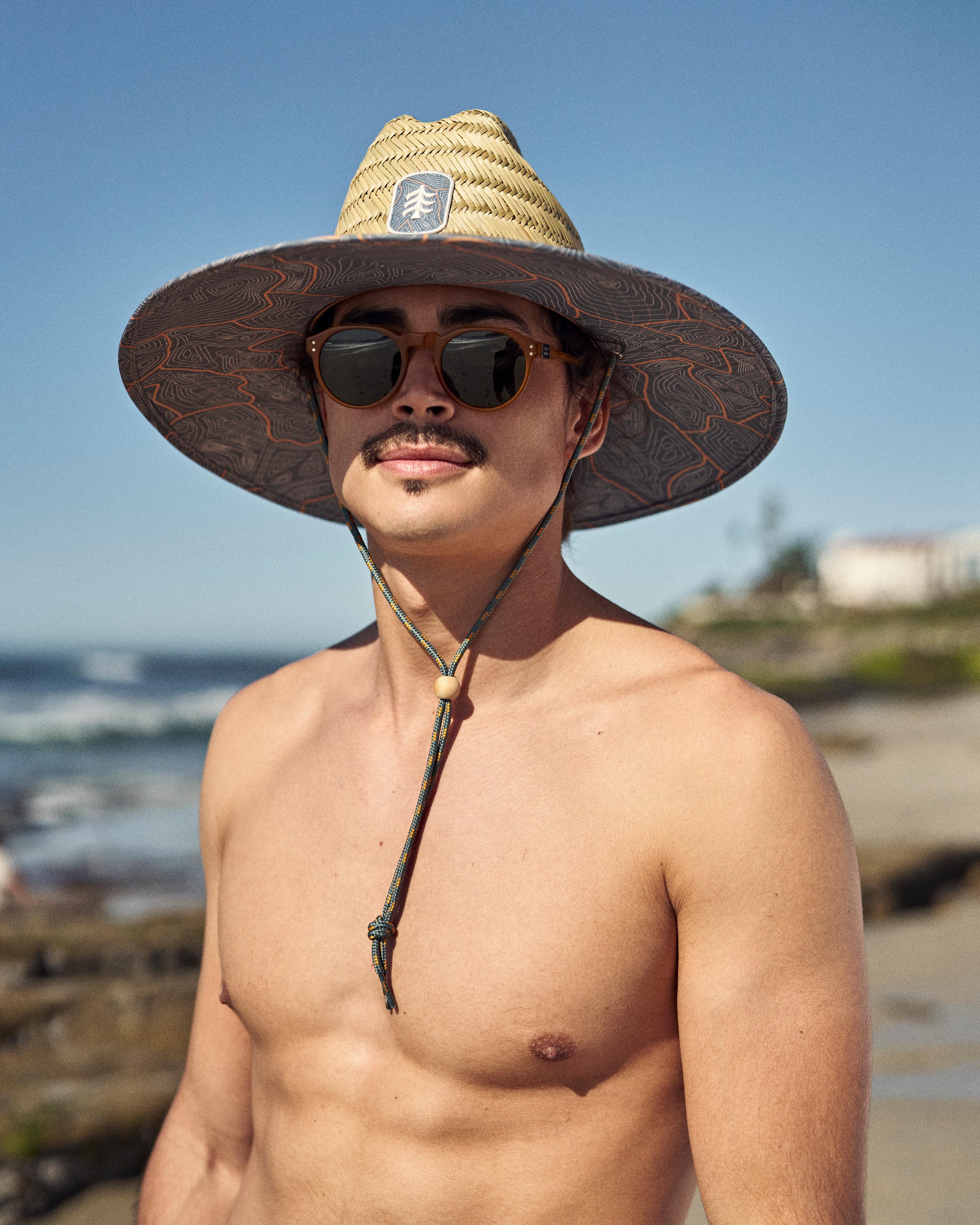 Hemlock male model wearing the UPF50+ Lifeguard Straw Hat Nomad Topography at the beach